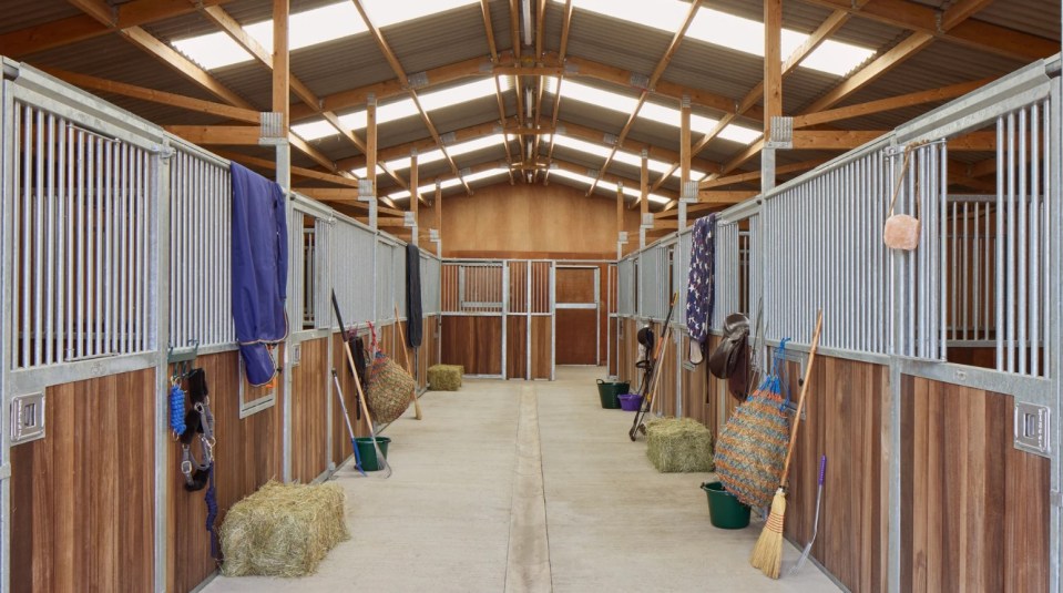 the inside of a horse stable with hay bales and brooms