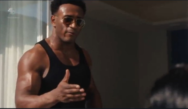 a man wearing sunglasses and a black tank top gives a thumbs up