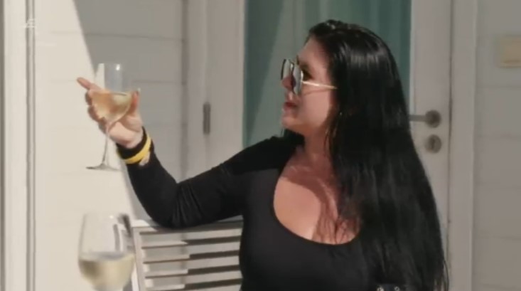 a woman is holding a glass of wine and pointing at it .