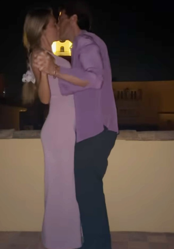 a man in a purple shirt kisses a woman in a purple dress