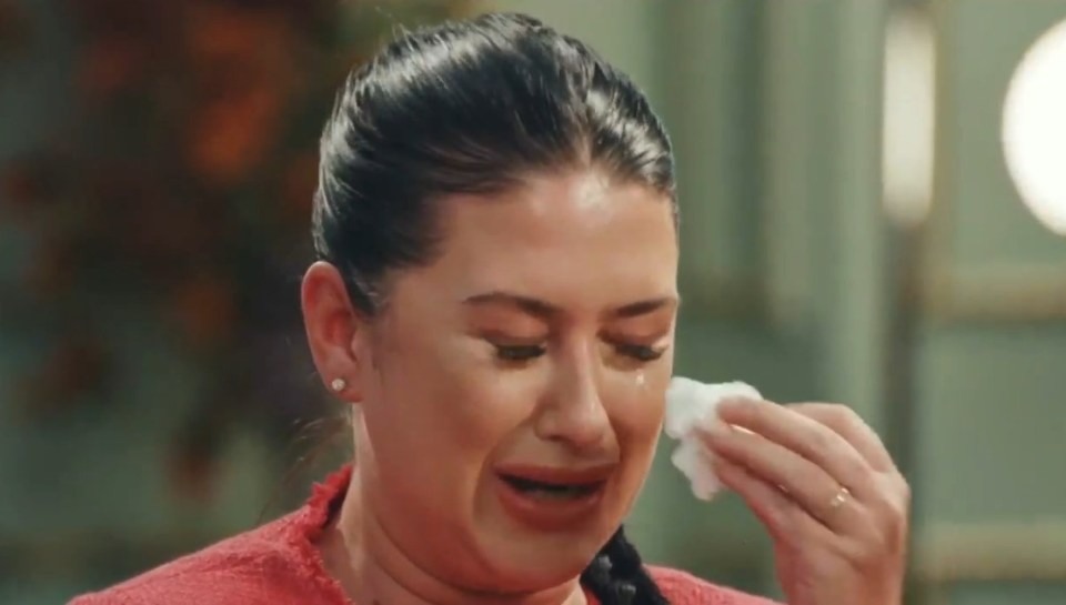 a woman is crying and wiping her eyes with a napkin .