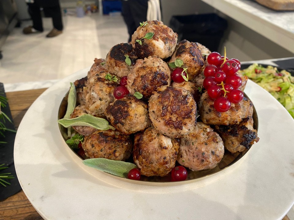 a plate of meatballs with sage and red currants on top