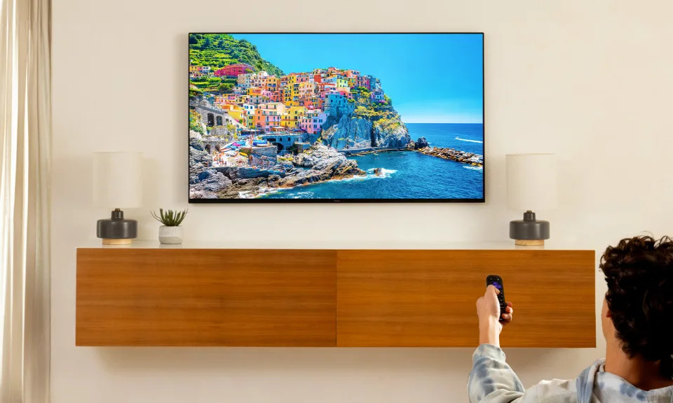 a man is holding a remote control in front of a flat screen tv