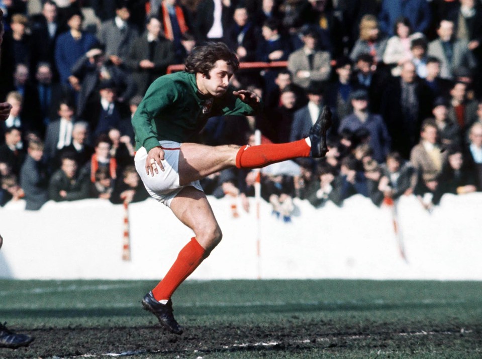 a soccer player kicking a ball in front of a crowd