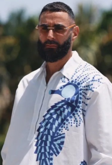 a man with a beard wearing sunglasses and a white shirt with a blue seahorse on it