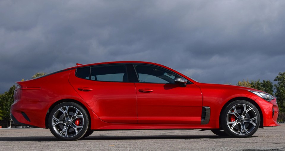 a red car is parked in a parking lot on a cloudy day