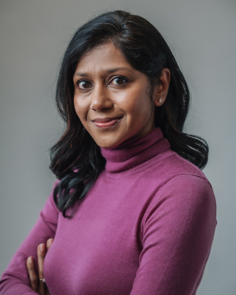 a woman in a purple turtleneck smiles for the camera