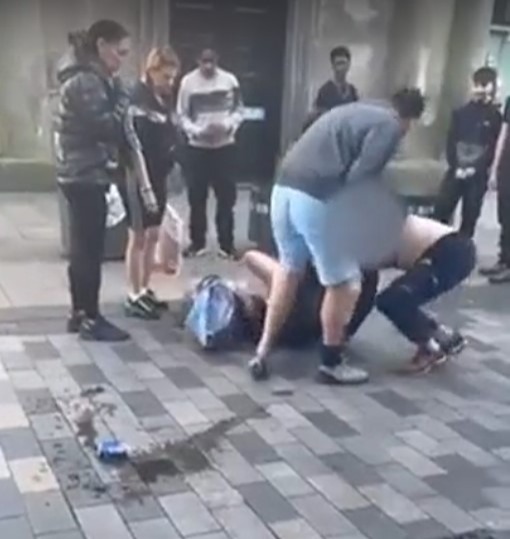 a group of people are standing around a man laying on the ground .