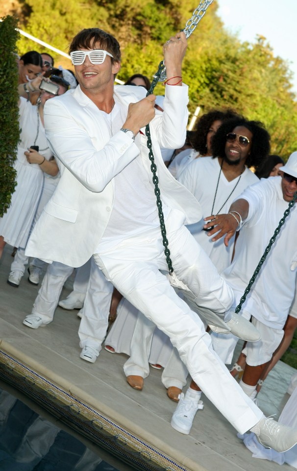 a man in a white suit swings on a chain