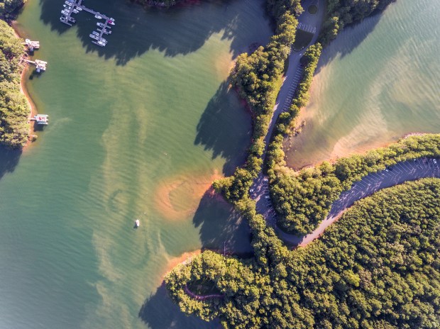 an aerial view of a lake surrounded by trees and boats