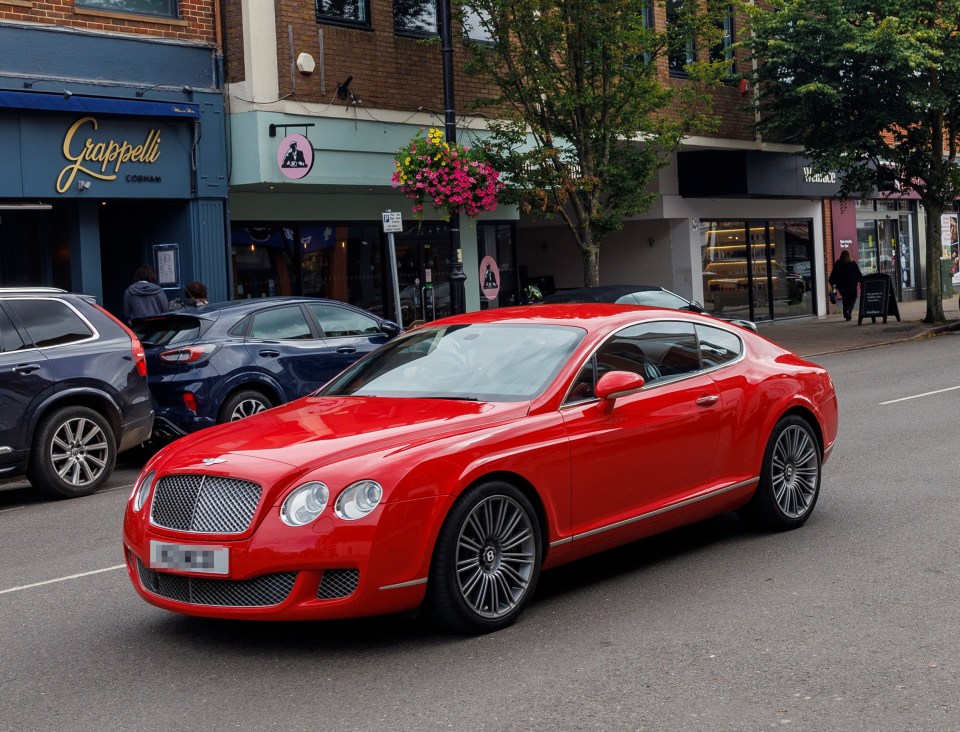 a red car is driving down a street in front of a shop called grappelli