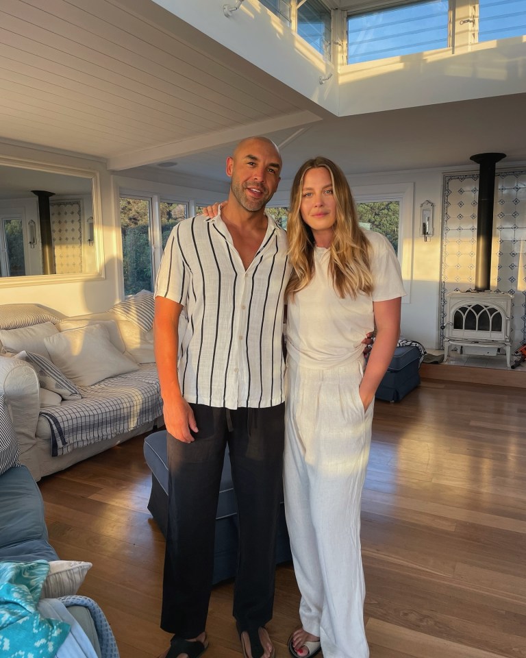 a man and a woman pose for a picture in a living room