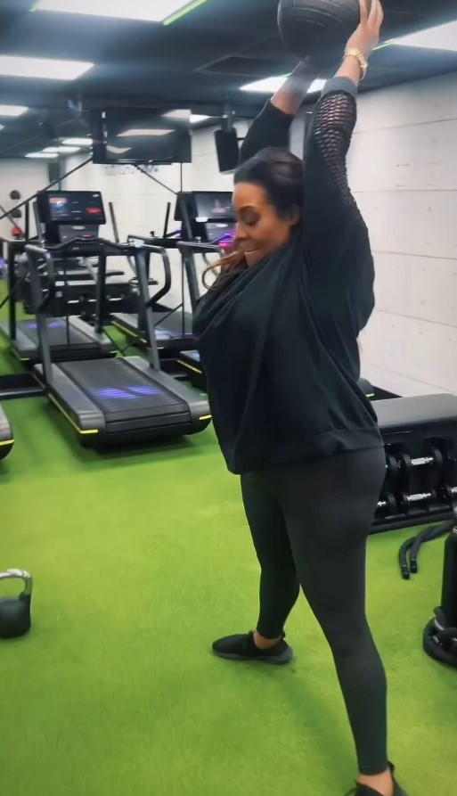 a woman is lifting a ball over her head in a gym .