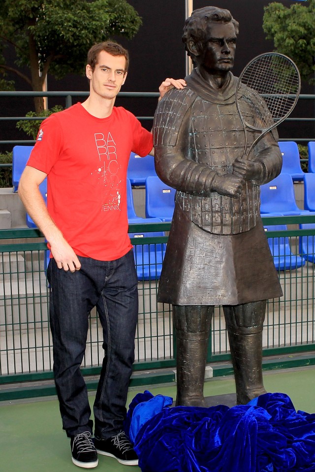 a man standing next to a statue of a man holding a tennis racquet