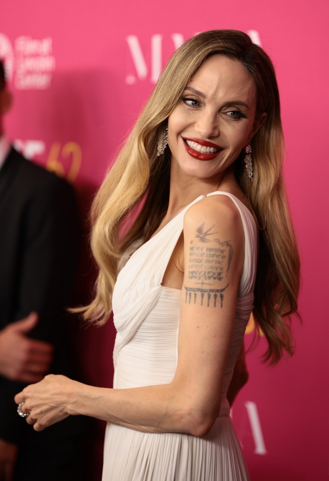 a woman in a white dress has a tattoo on her arm