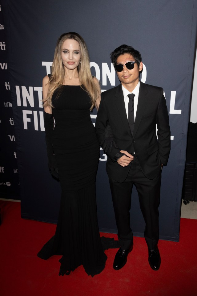 a woman in a black dress stands next to a man in a suit