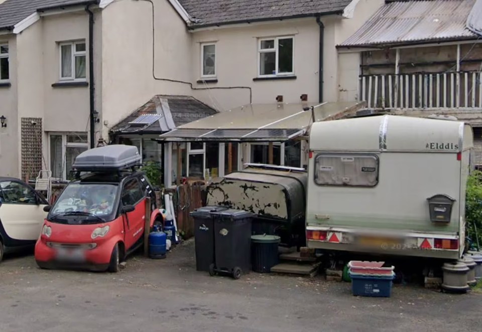 The van sitting on the driveway surrounded by bins and other debris