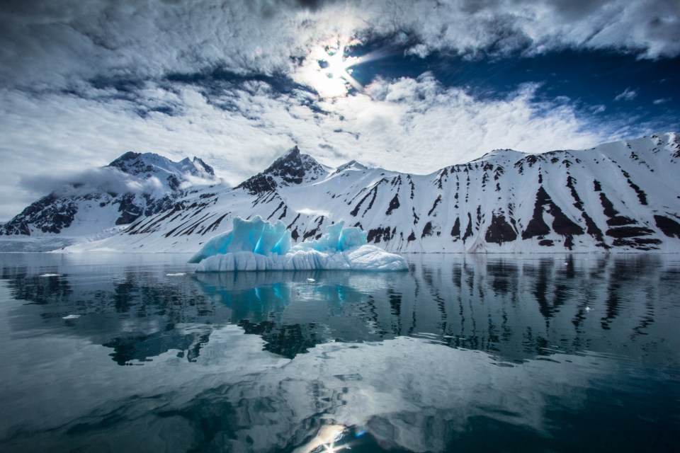 a large iceberg in the middle of a lake with mountains in the background