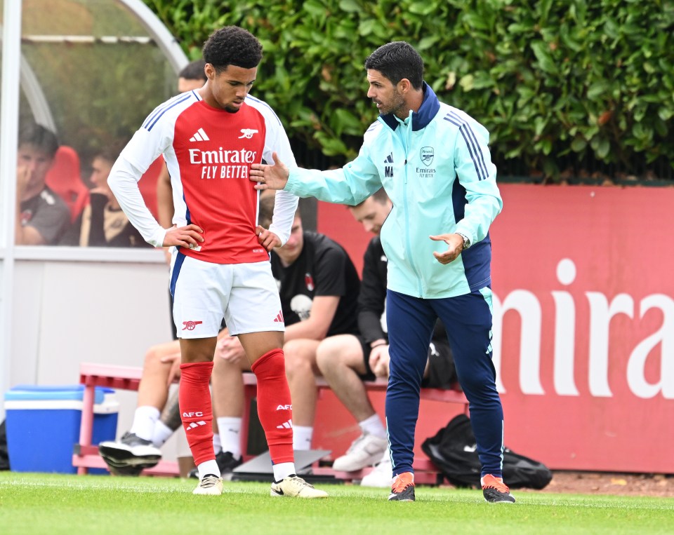 a soccer player wearing an emirates fly better shirt talks to another player