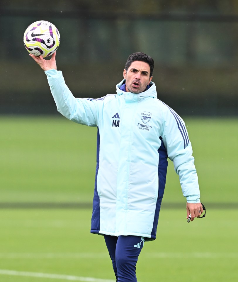 a man in an arsenal jacket holds a soccer ball in his hand