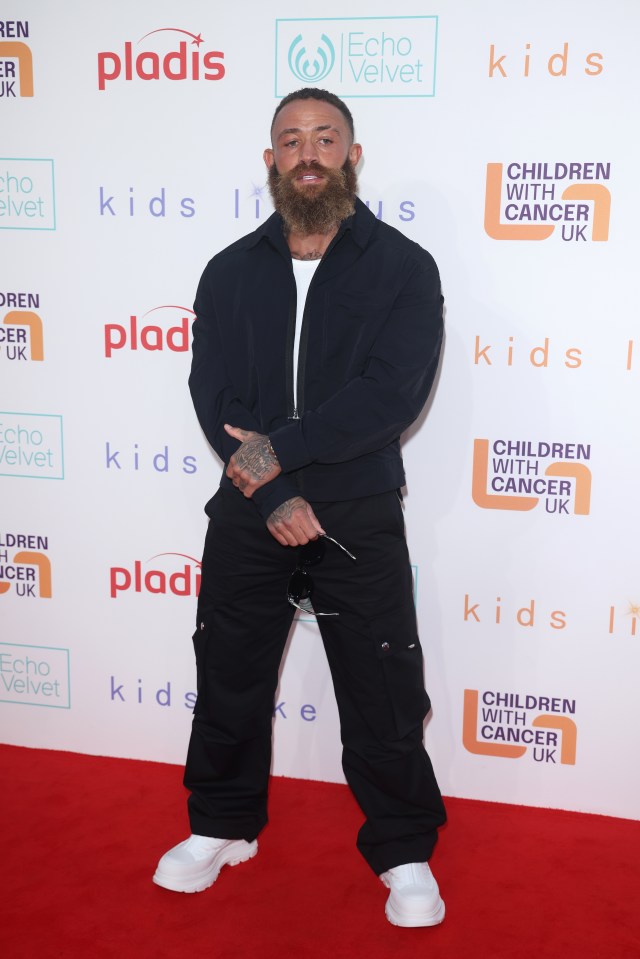 a man with a beard is standing on a red carpet for children with cancer uk