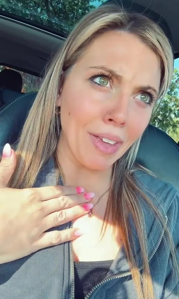 a woman sitting in a car with her hand on her chest