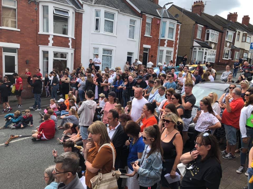 a crowd of people are gathered on the side of a street watching a parade