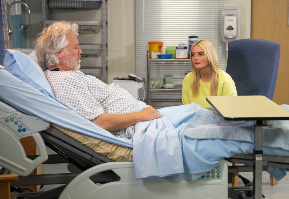 a woman sits next to an older man in a hospital bed