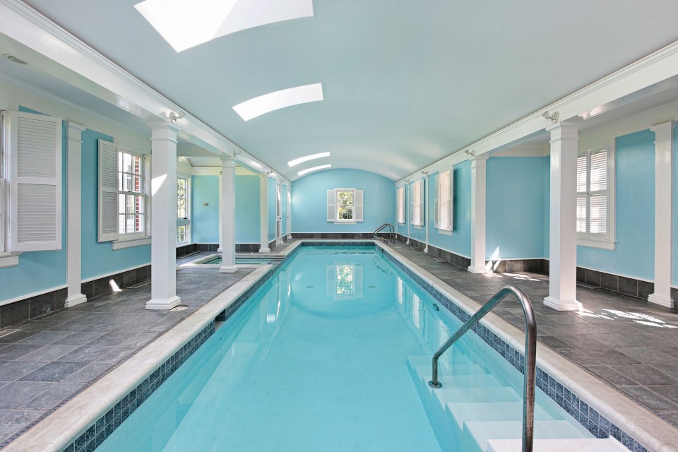 an indoor swimming pool with blue walls and white shutters