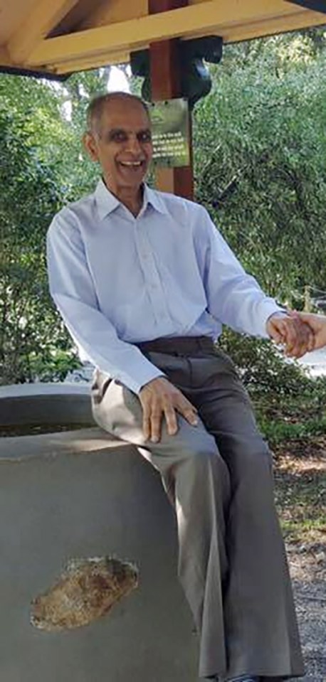 a man is sitting on a bench in a park shaking hands with another man .