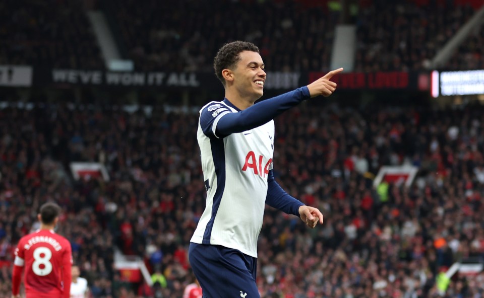 a soccer player wearing a white aia jersey points to the crowd