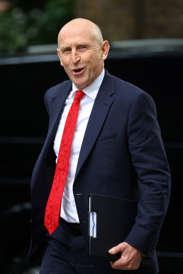 a man in a suit and red tie holds a folder