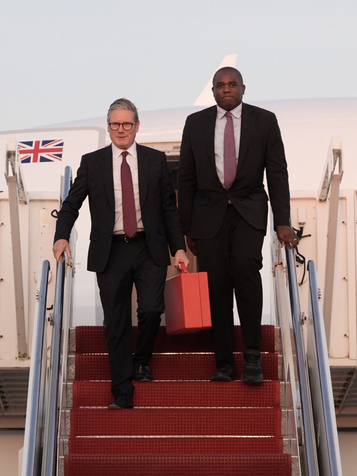 two men are walking up the stairs of an airplane with a british flag on the side