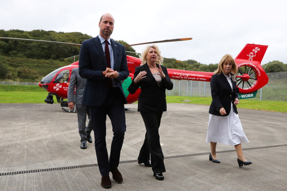 a group of people walking in front of a red helicopter that says emergency medical services