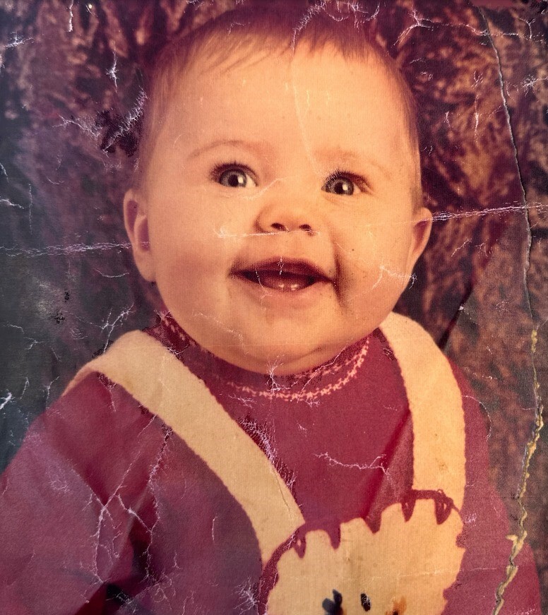 a baby in a red and white sweater smiles for the camera