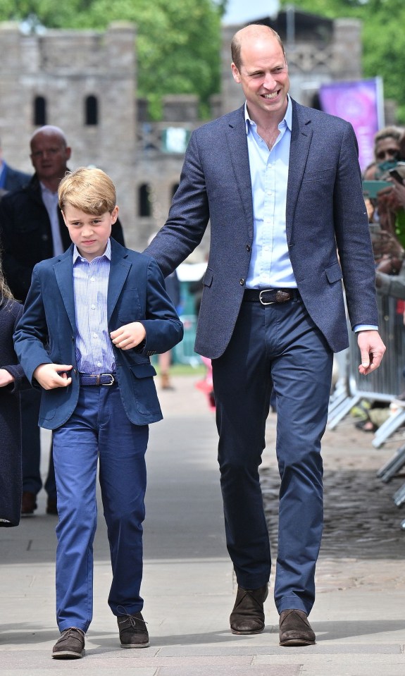 a man in a suit and a boy in blue pants walk down a street