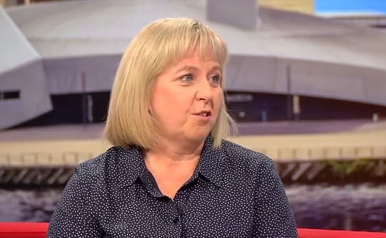 a woman is sitting on a red couch talking on a television show .