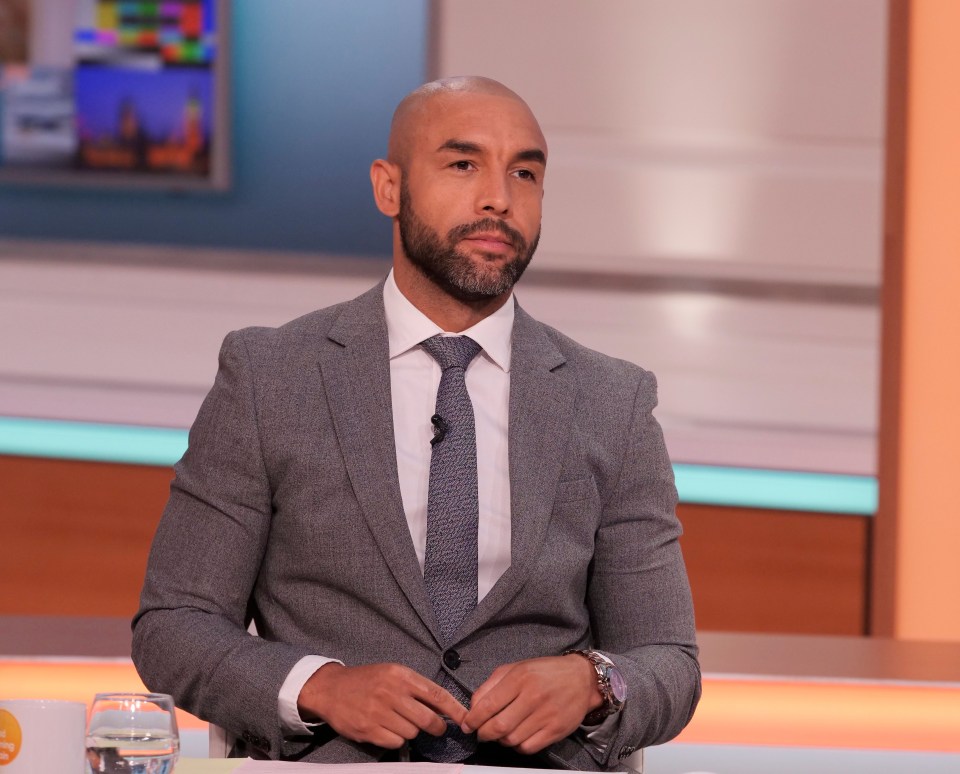 a man in a suit and tie sits at a table with a glass of water