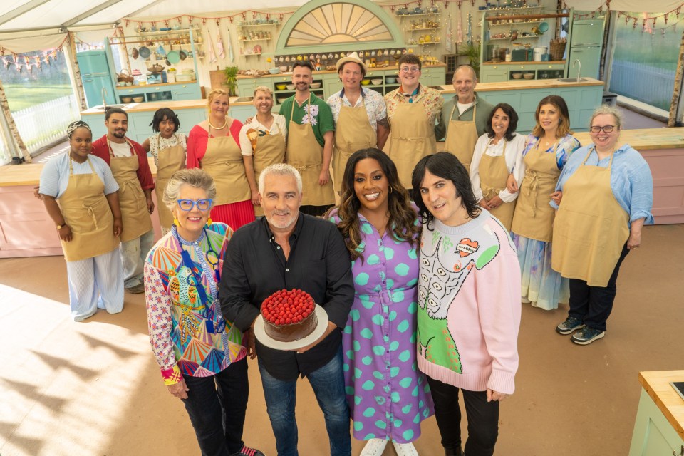 a group of people posing for a picture with one man holding a cake