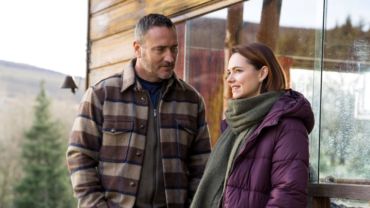 a man in a plaid jacket and a woman in a purple jacket are standing next to each other