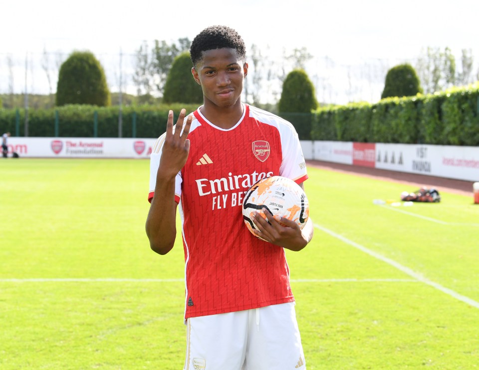 a soccer player wearing an emirates jersey holds a soccer ball