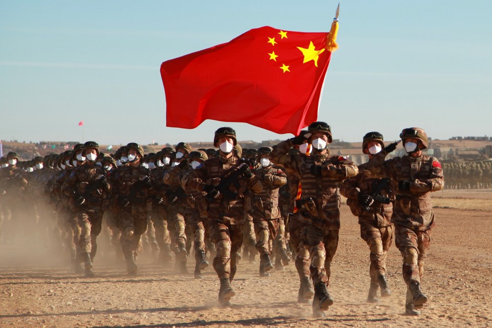 a group of soldiers marching with a flag in the background