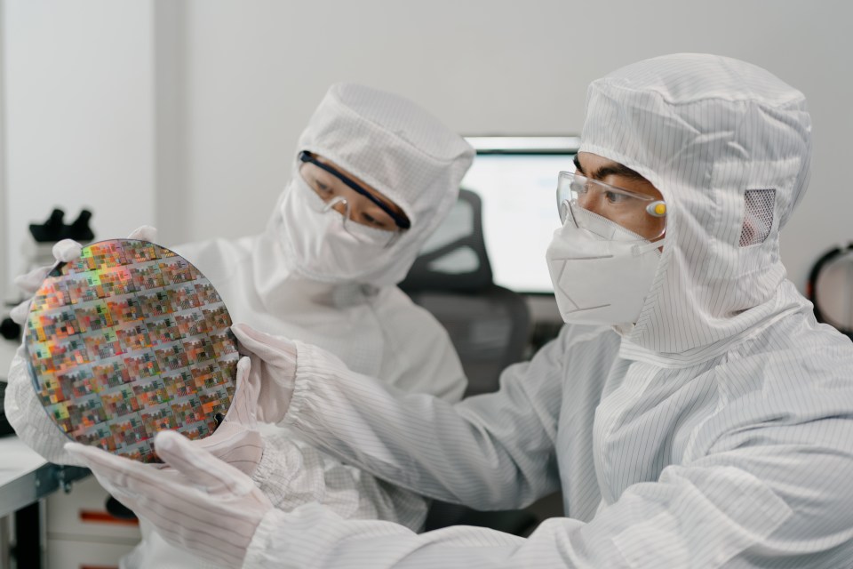 a man in a lab coat is holding a semiconductor chip