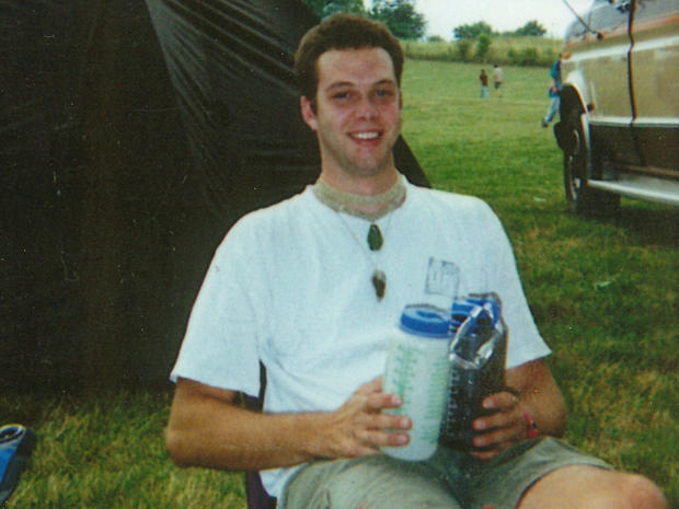 a young man is smiling for the camera while standing next to a woman .