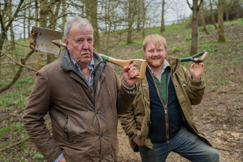 a man holding a shovel stands next to another man