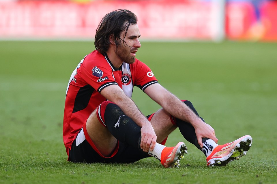 a soccer player sits on the field with a g on his jersey