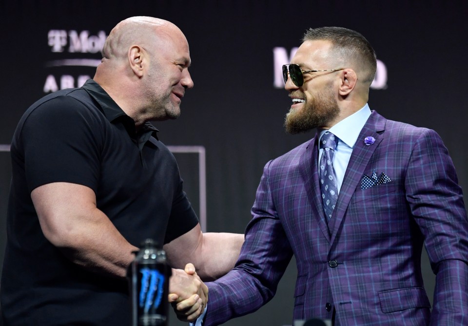 two men shaking hands in front of a sign that says t mobile