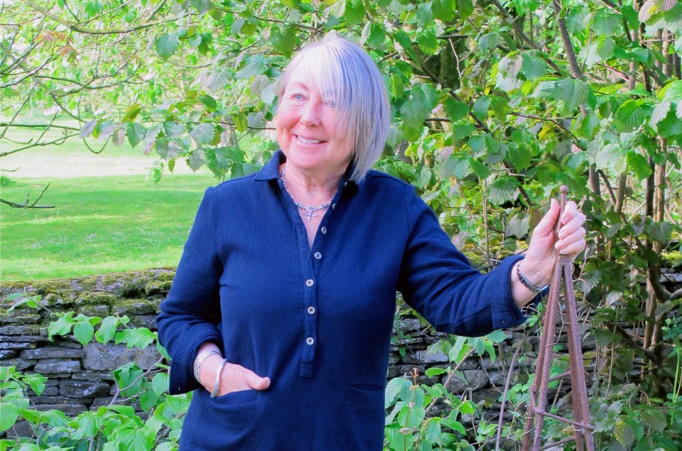 a woman in a blue shirt is smiling and holding a plant