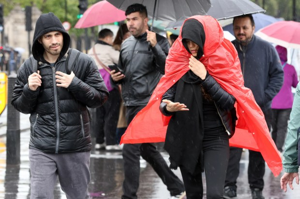 a woman in a red cape is walking in the rain