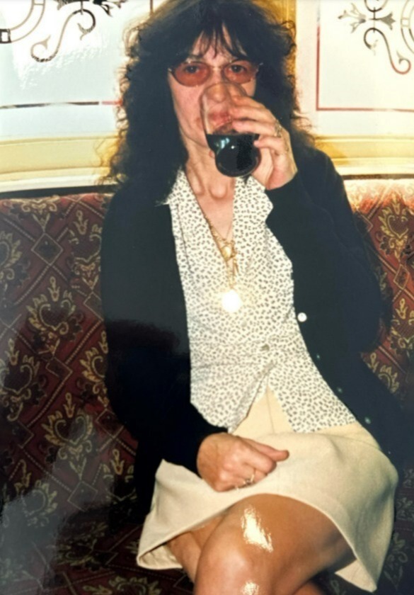 a woman sits on a couch drinking a glass of wine